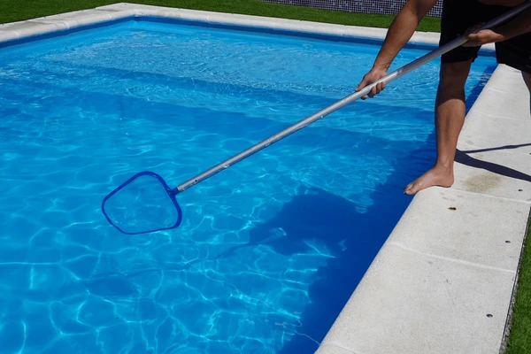 Technician skimming leaves and brushing the pool, keeping water clear and healthy in Ohio.